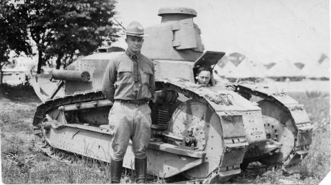 Dwight D. Eisenhower stands by a tank.