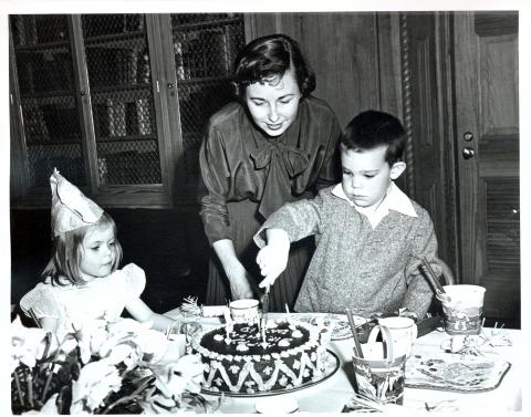 5th Birthday party for David Eisenhower held in the Library of the White House. David is cutting his cake while Mother looks on. Washington, DC, March 31, 1953 [72-172-1]