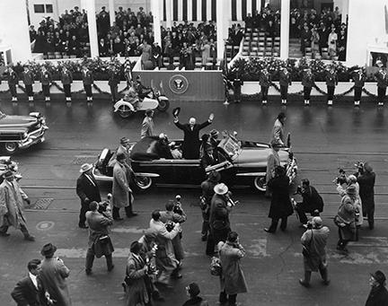 January 21, 1957 - Dwight D. Eisenhower waves to the crowd as he arrives at the inaugural parade reviewing stand
