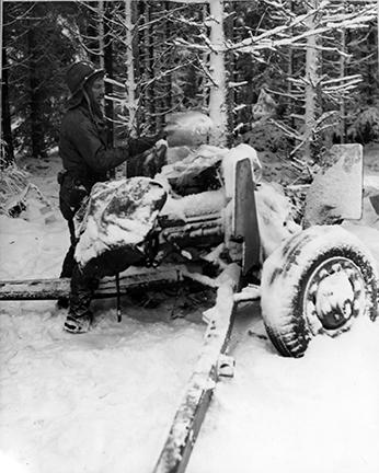 Ardennes-Battle of the Bulge. January 21, 1945 - Sgt. William Showers of Benezett, Pennsylvania, cleans the snow from the breech of his 57mm anti-tank gun in the woods near Courtil, Belgium.