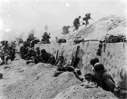 June 9, 1944 - Taking a "breather" after gaining comparative safety offered by a concrete wall, American troops of the 8th Infantry Regiment, 4th Infantry Division, move over the crest of a hill to the interior of Northern France