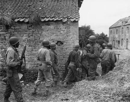 June 10, 1944 - Allied troops surround a farm house as they prepare to eliminate a German sniper holding up an advance on Omaha beachhead near Vierville-sur-Mer, France.