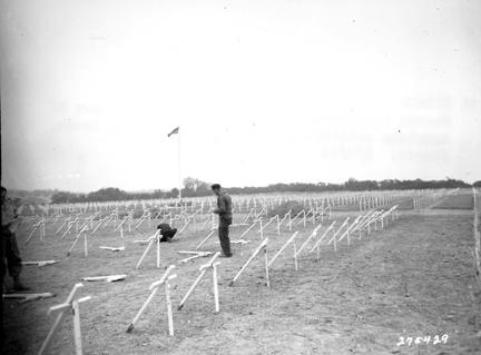 August 8, 1944 - French civilians place crosses at the graves of American soldiers in a cemetery on Omaha Beach, France