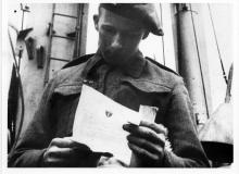 British soldier aboard ship reading Eisenhower's Order of the Day. Normandy, France, June 6, 1944. [70-233-3]