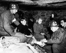 Ardennes-Battle of the Bulge. January 11, 1945 - Captain Charles S. Quinn (right) of Louisville, Kentucky, bandages gangrene infected foot of Belgian refugee child in cellar of house in Ottre, Belgium. Captain Quinn is a battalion surgeon with the 83rd Division, First Army.