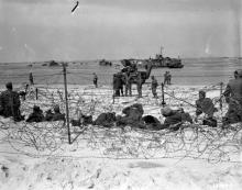 June 6, 1944 - German prisoners rest in a barb-wired enclosure on Utah Beach after being interrogated by American soldiers