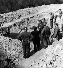 April 12, 1945 - Dwight D. Eisenhower, Omar Bradley, and George Patton are given a tour of Ohrdruf concentration camp. Here they visit a burial pit containing the charred remains of prisoners who were burned to death at Ohrdruf.